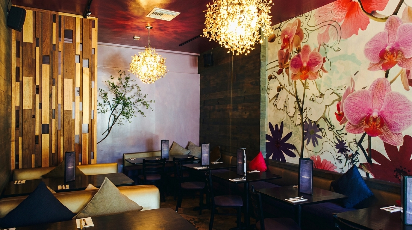 Cozy restaurant interior with modern chandeliers, wooden accents, and a large floral mural with pink orchids.