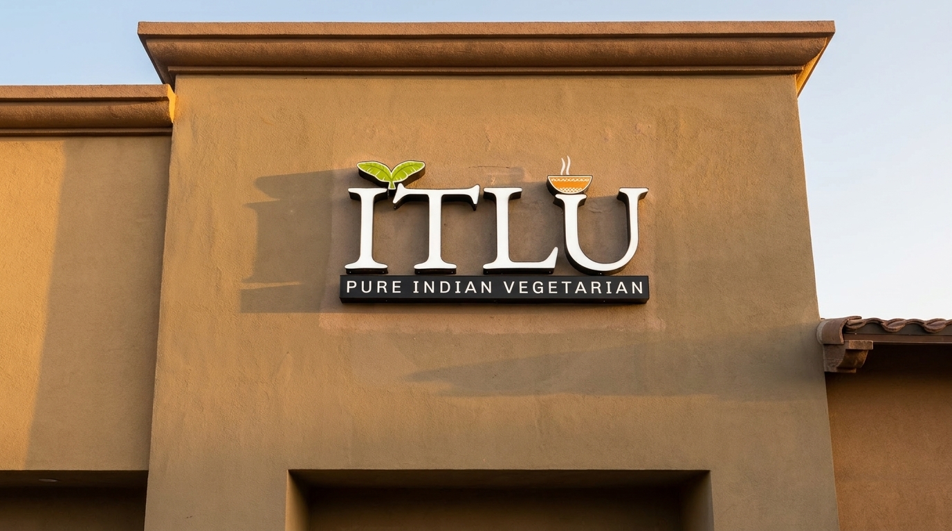 ITLU Pure Indian Vegetarian restaurant sign on a tan building with a clear sky.