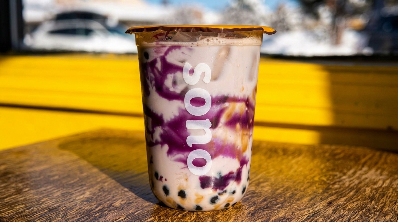 A Sono bubble tea with purple taro swirls and tapioca pearls sits on a wooden table.