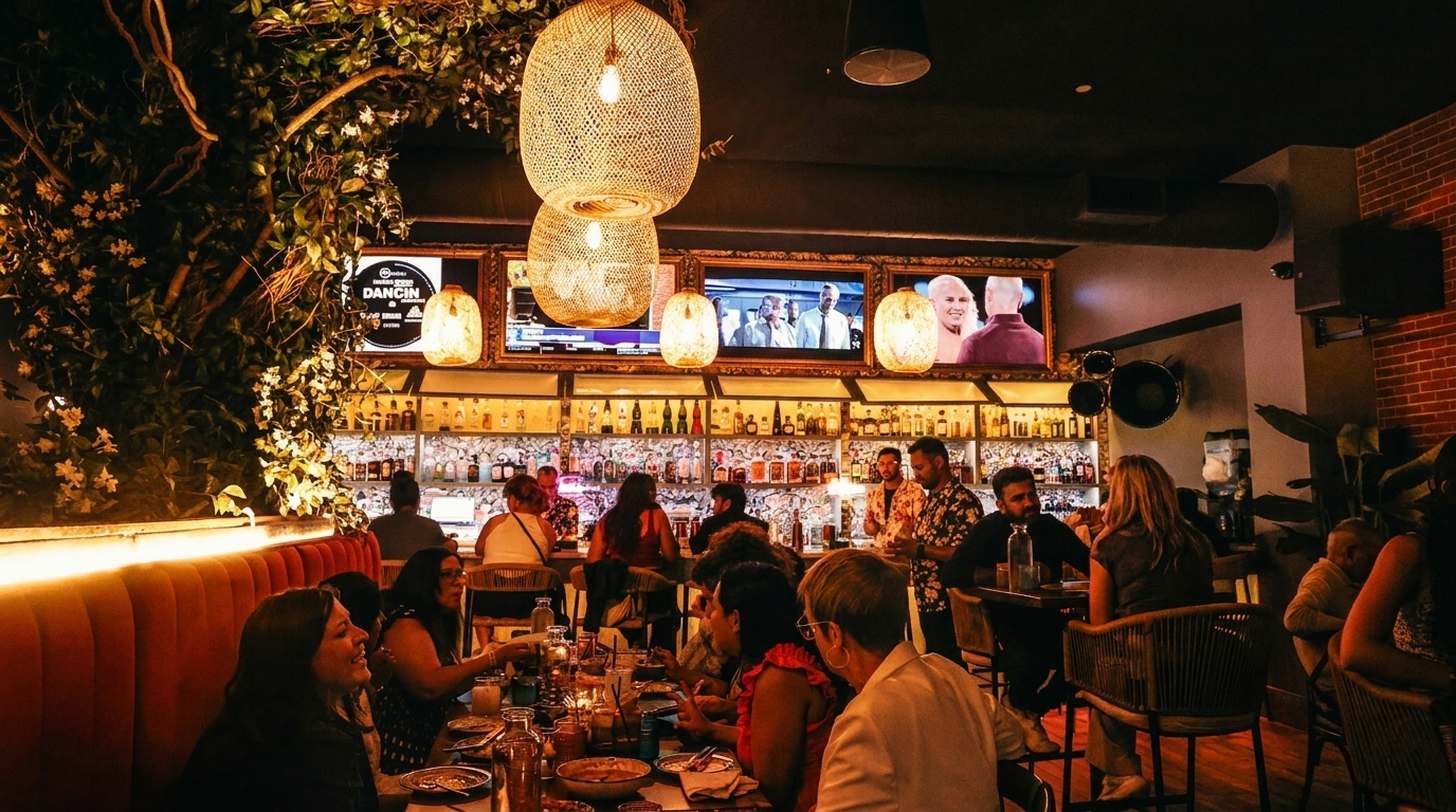 A lively restaurant interior with patrons dining and drinking at tables and a bar.