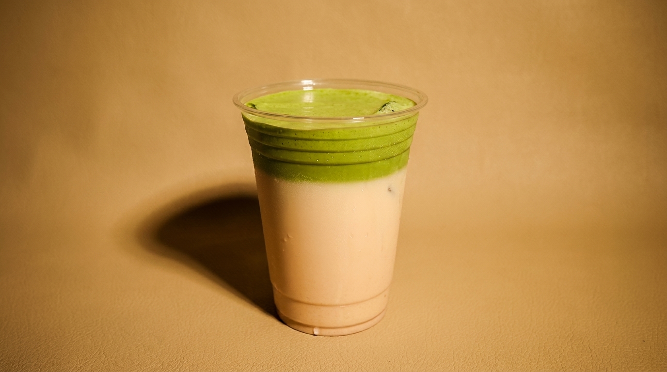 Iced matcha latte in a clear plastic cup with distinct green and white layers.