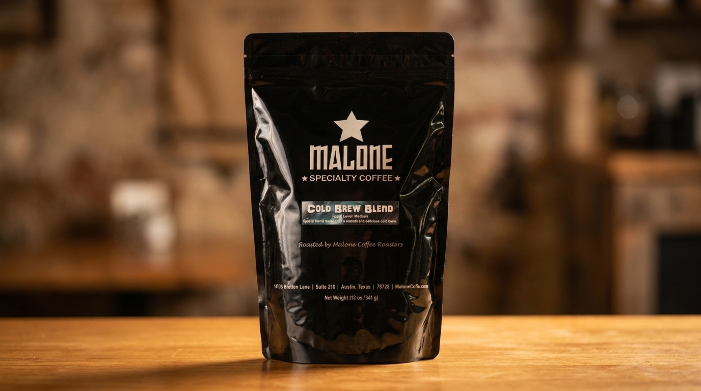 A black bag of Malone Cold Brew Blend coffee stands on a wooden surface.
