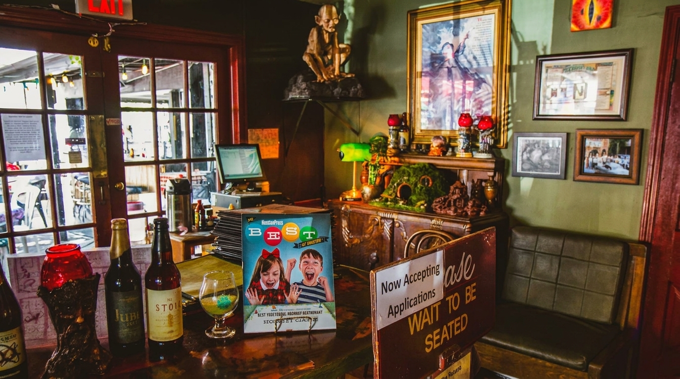 A restaurant's eclectic interior with a counter, bottles, a "Best of Boston" magazine, and fantasy-themed decor.