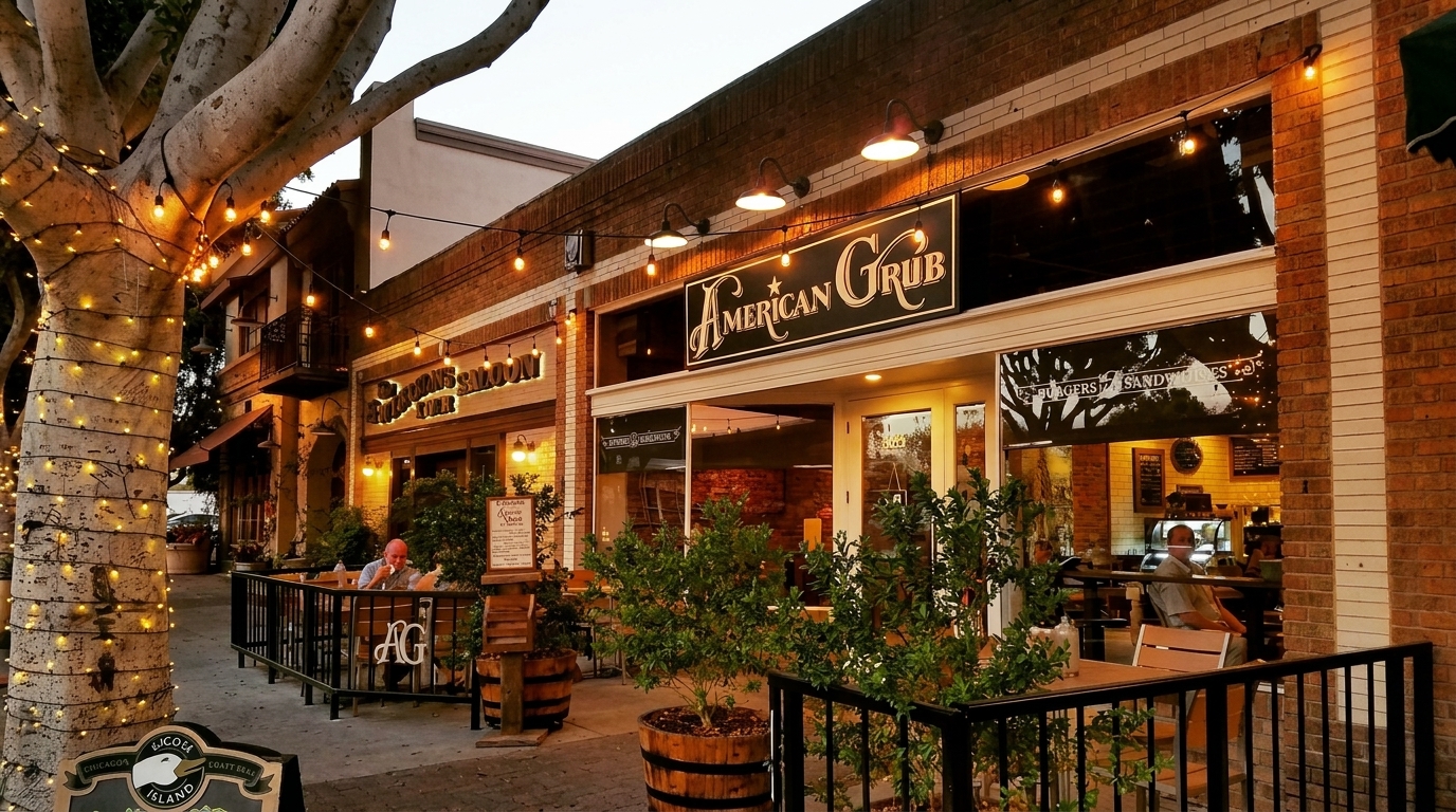 Exterior of American Grub restaurant at dusk, with string lights on a tree and patio seating.