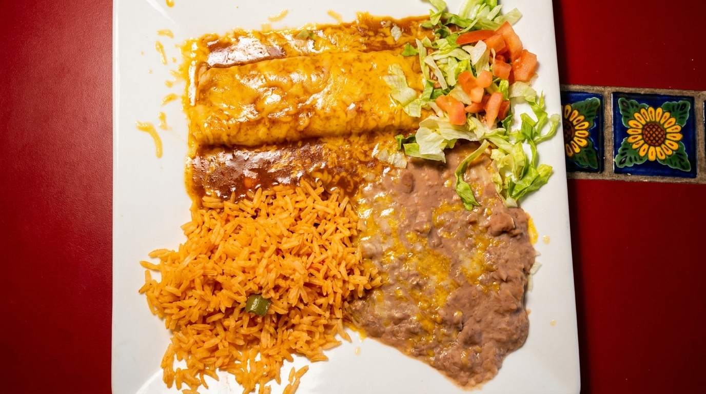 Two cheese enchiladas with red sauce, rice, refried beans, and a side salad on a white plate.