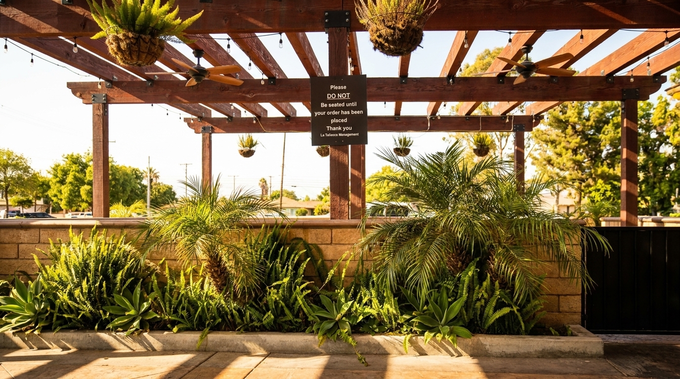 Outdoor patio with wooden pergola, hanging plants, ceiling fans, and lush green landscaping.