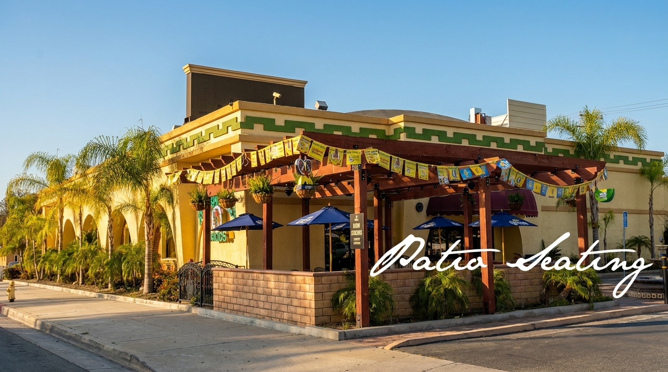 Exterior of a vibrant Mexican restaurant with a covered patio, blue umbrellas, and palm trees.
