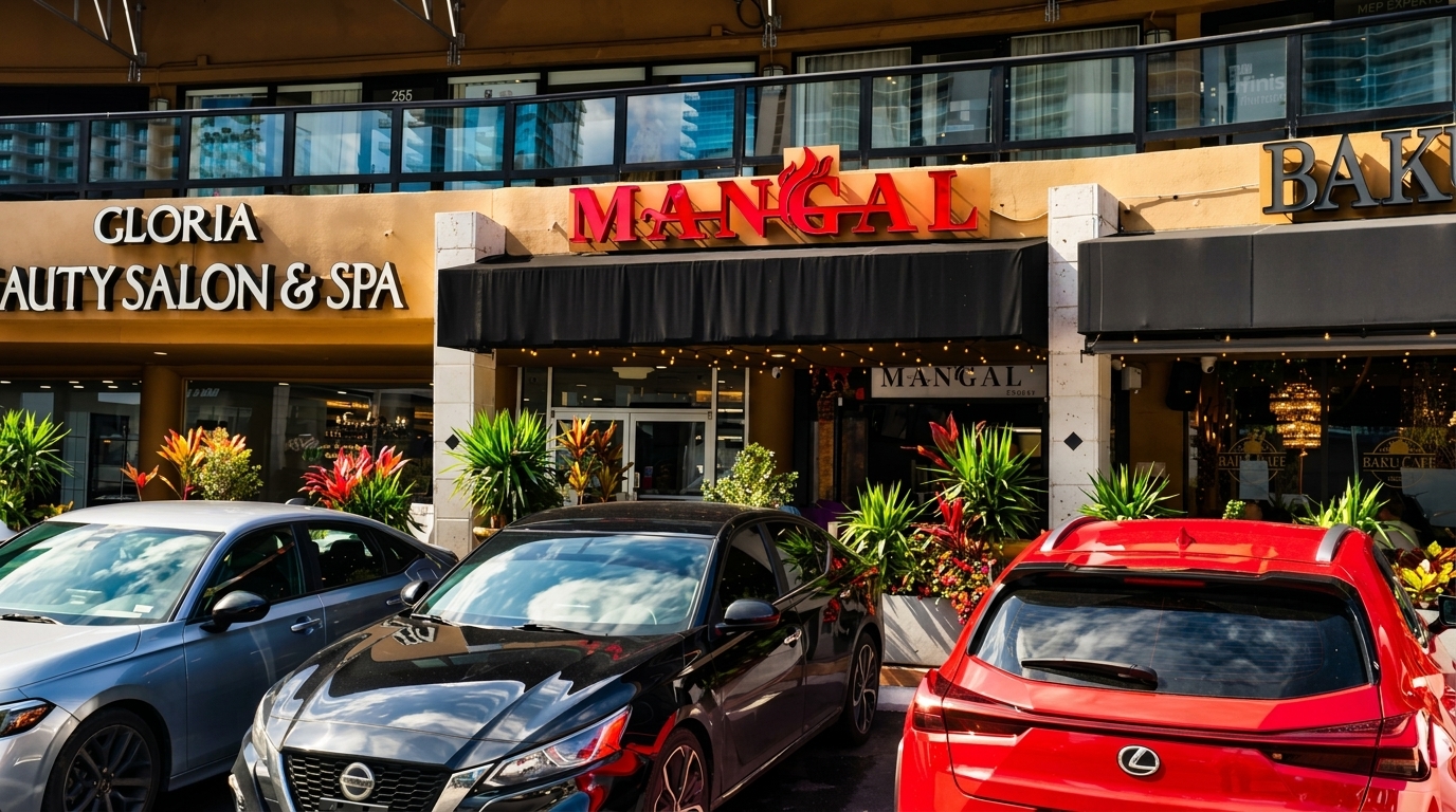 Exterior of Mangal restaurant with a black awning, red sign, and cars parked in front.