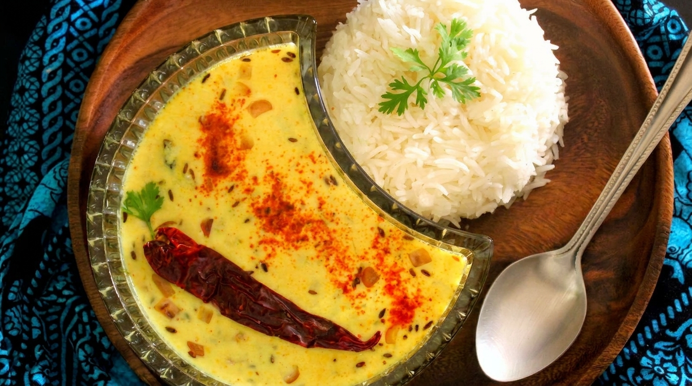 Creamy yellow curry with a red chili and spices, served with white rice and a spoon.