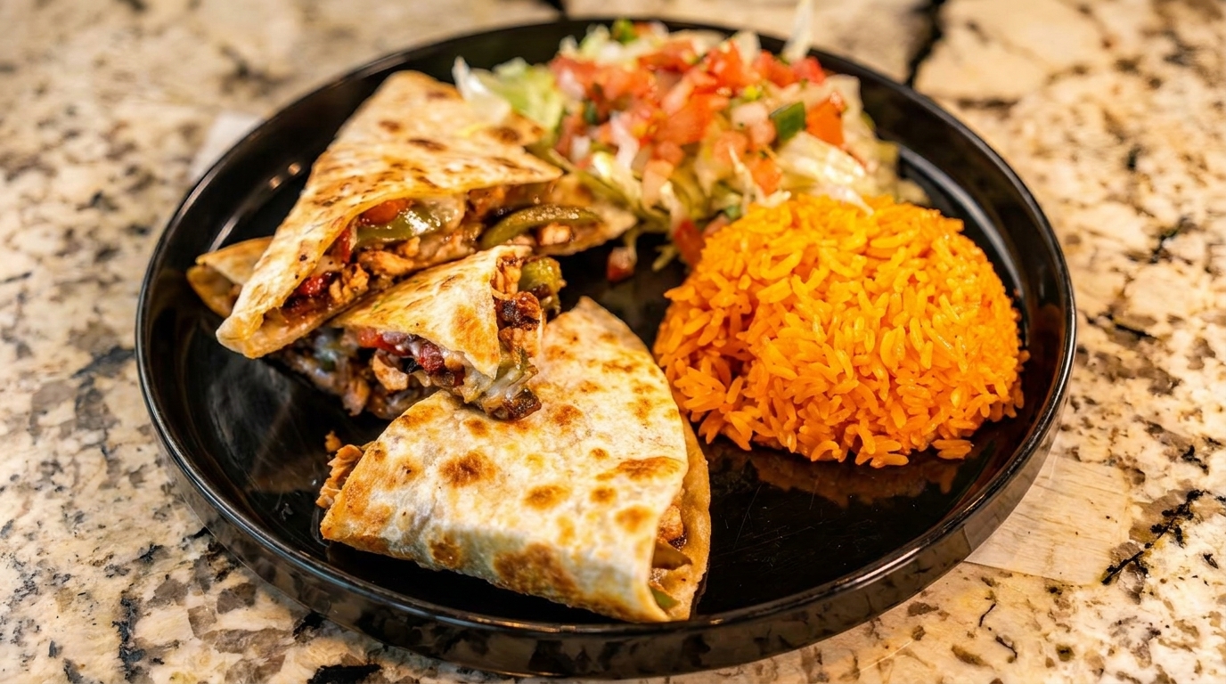 Chicken quesadillas with bell peppers, rice, and a side salad on a black plate.