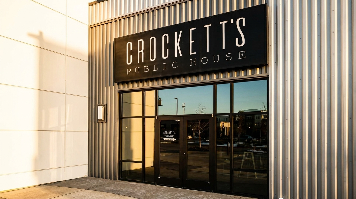 Exterior of Crockett's Public House with a black sign and large glass doors reflecting the sky.