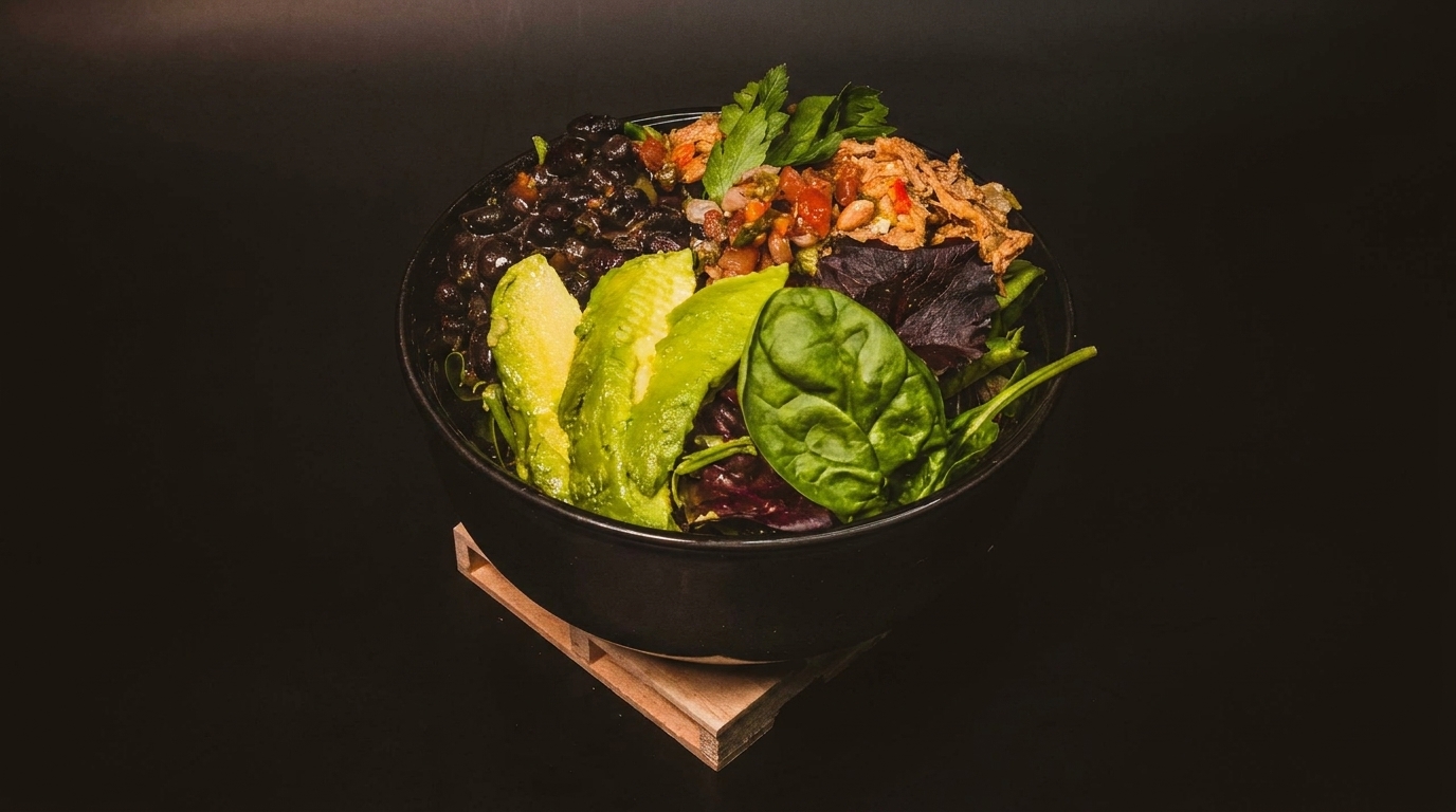 A vibrant salad bowl with black beans, avocado slices, mixed greens, salsa, and crispy fried onions.