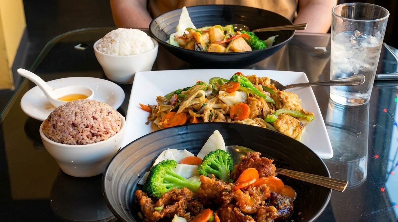 A table set with multiple bowls and plates of Asian cuisine, including rice, noodles, and stir-fries.