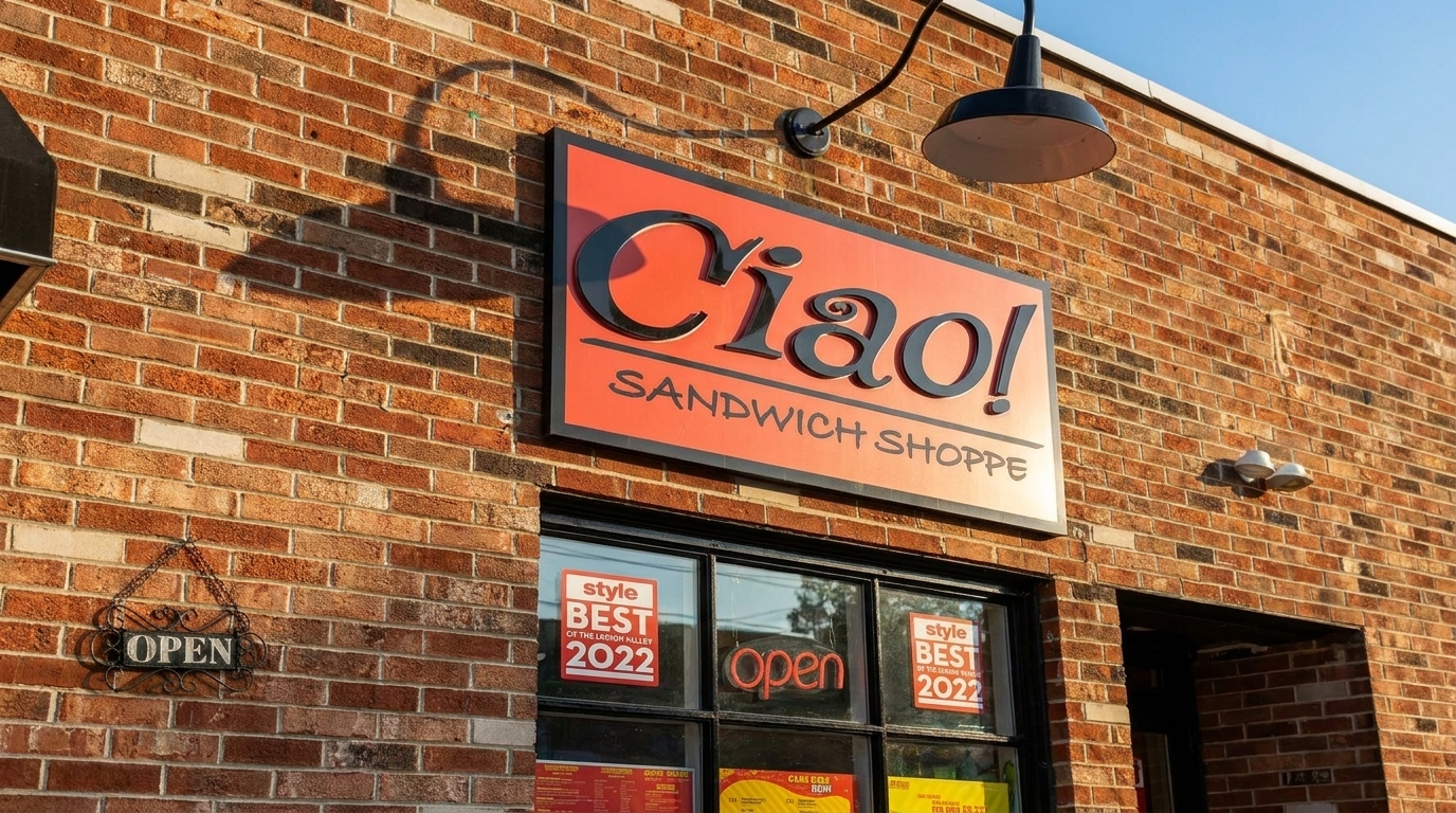 Ciao! Sandwich Shoppe sign on a brick building with "Open" signs in the windows.