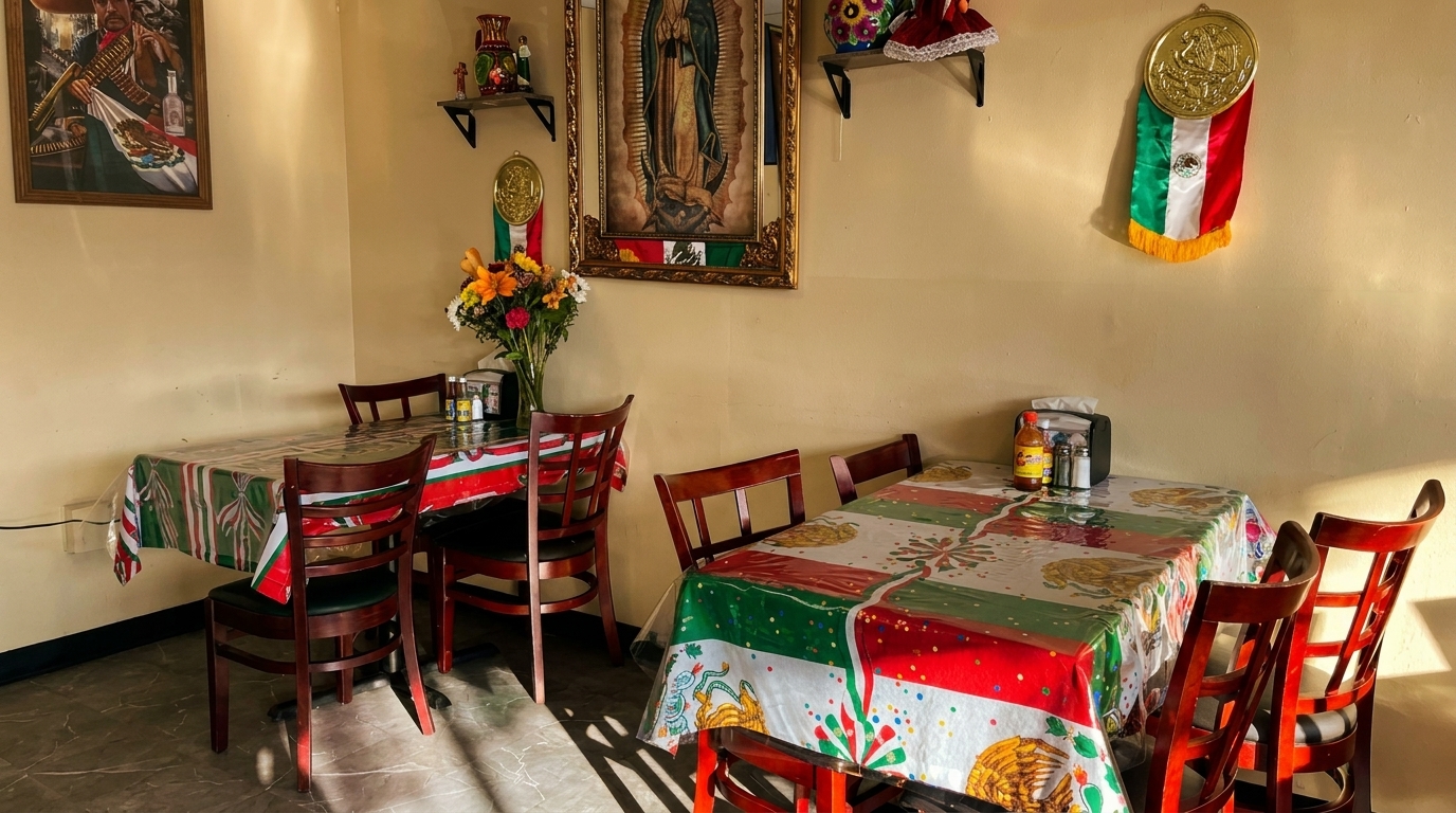 A brightly lit Mexican restaurant dining room with tables, chairs, and cultural decorations on the walls.