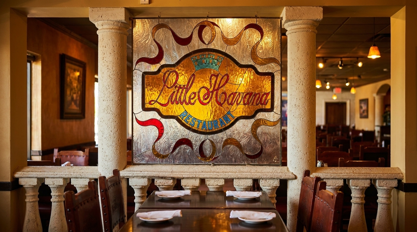 Stained glass "Little Havana Restaurant" sign above a dining area with tables and chairs.