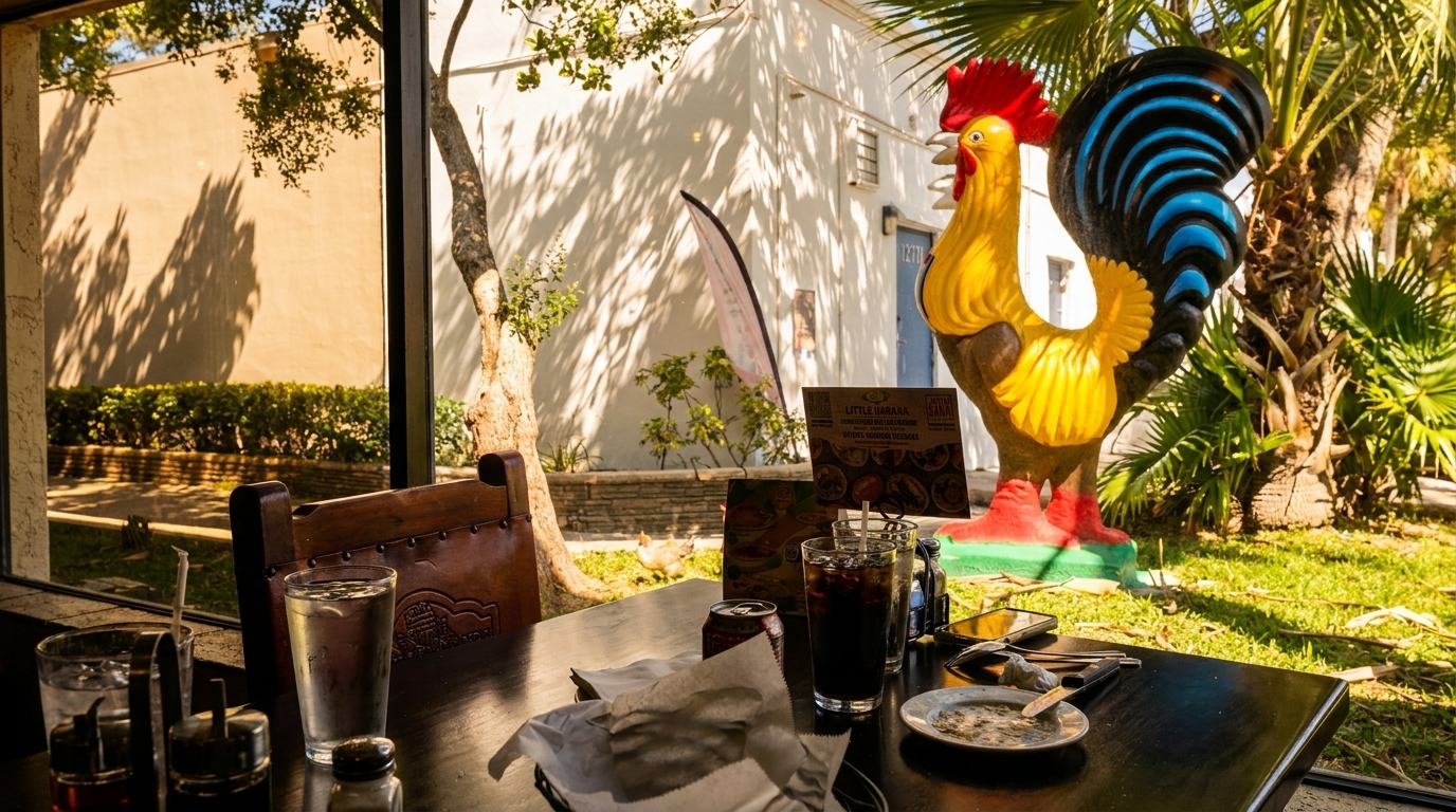 Restaurant table with drinks and menus, looking out a window at a large rooster statue.
