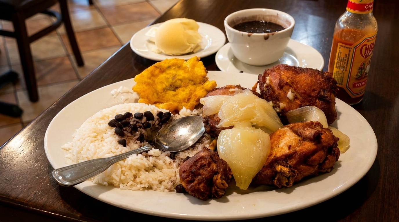 A Cuban meal with fried chicken, rice, black beans, plantains, and pickled onions.