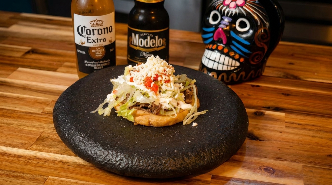 A Mexican sope with meat, lettuce, cheese, and crema, with two beer bottles and a skull.