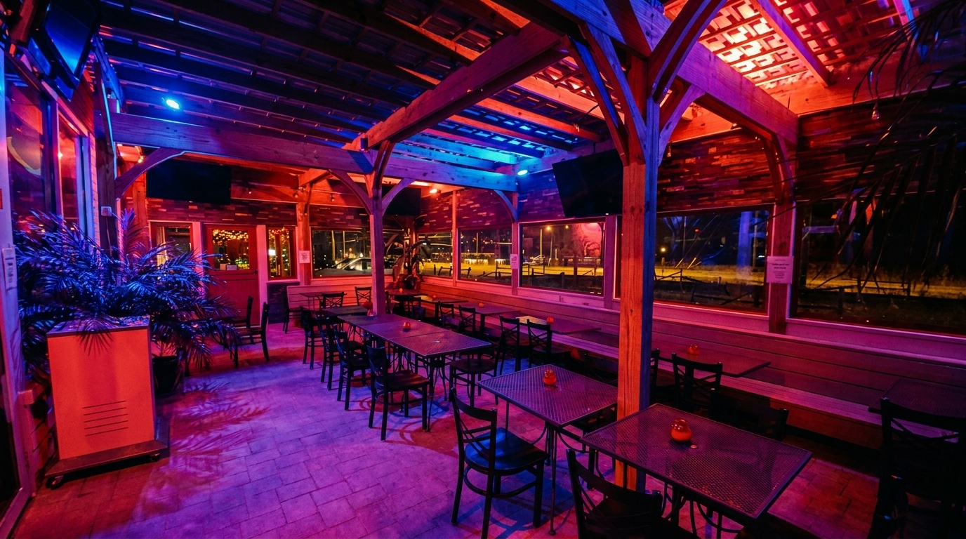 Restaurant patio with metal tables and chairs, illuminated by vibrant red and blue lighting.
