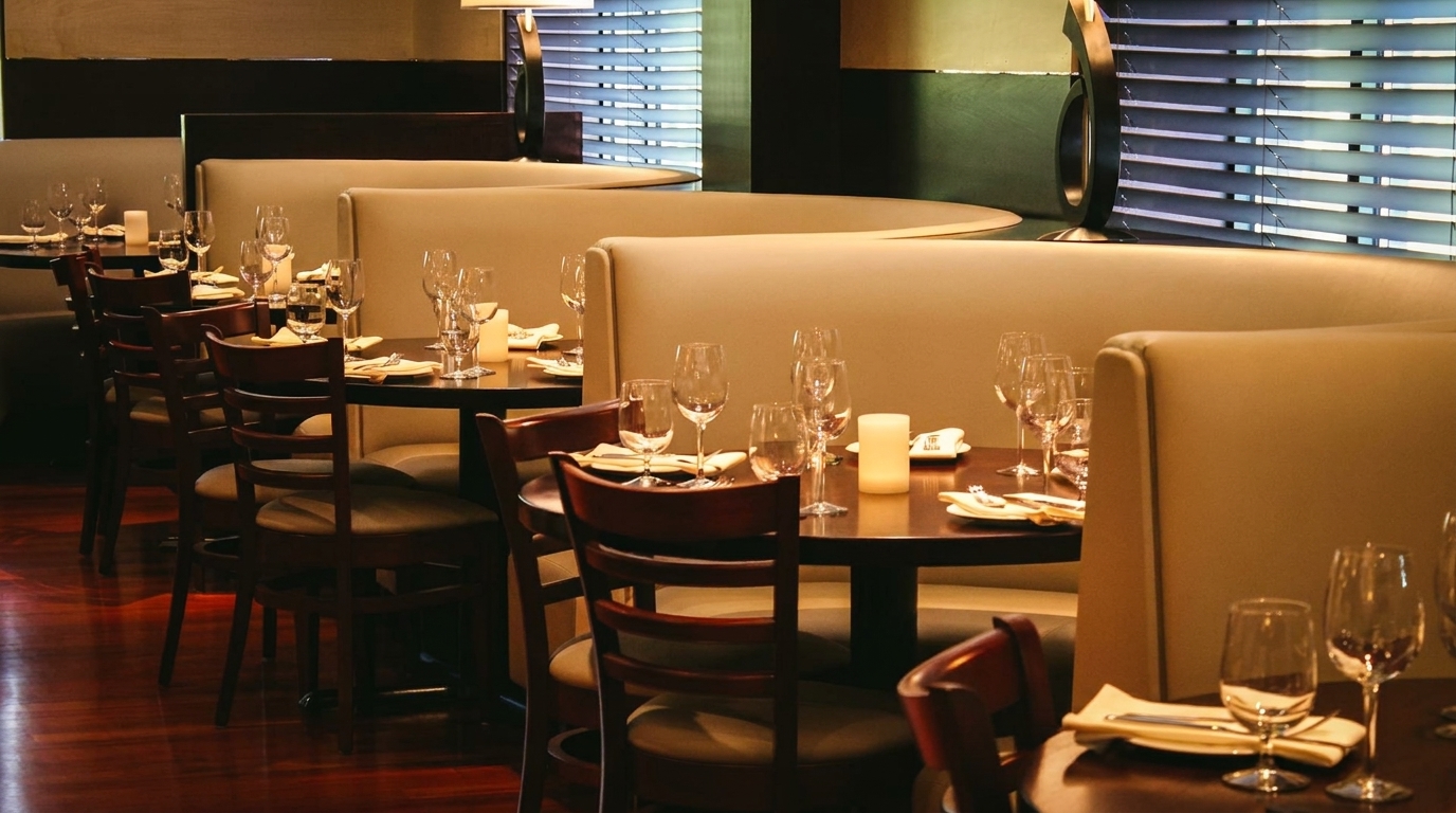 Elegant restaurant dining room with set tables, plush booths, and warm lighting, ready for guests.