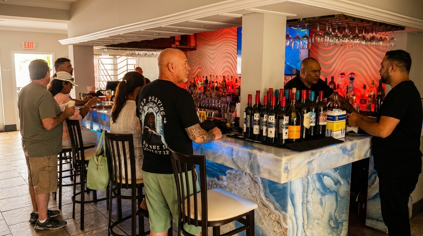 Patrons gather at a lively bar with a blue and white marble counter and a bartender serving drinks.