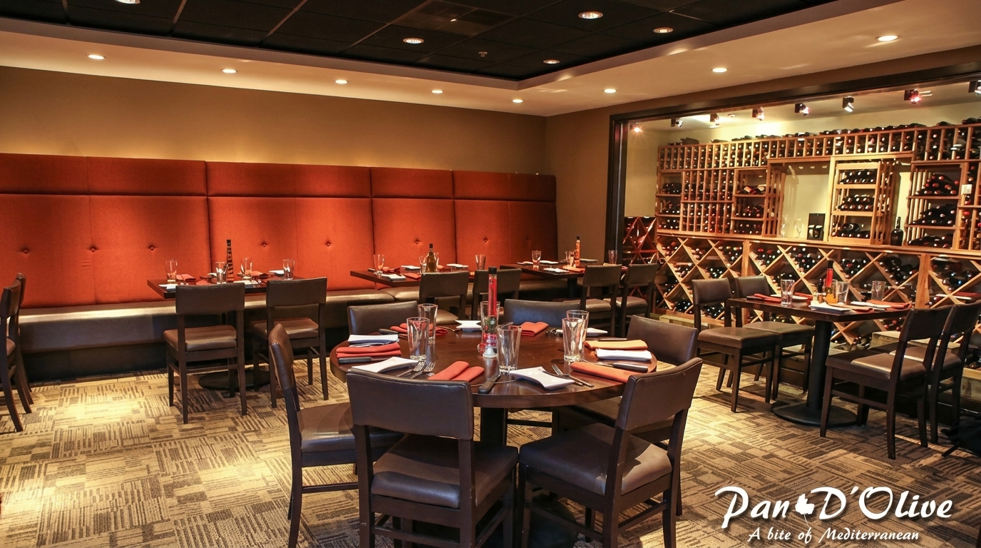 Restaurant dining room with orange booth seating, dark tables, and a large wine rack wall.