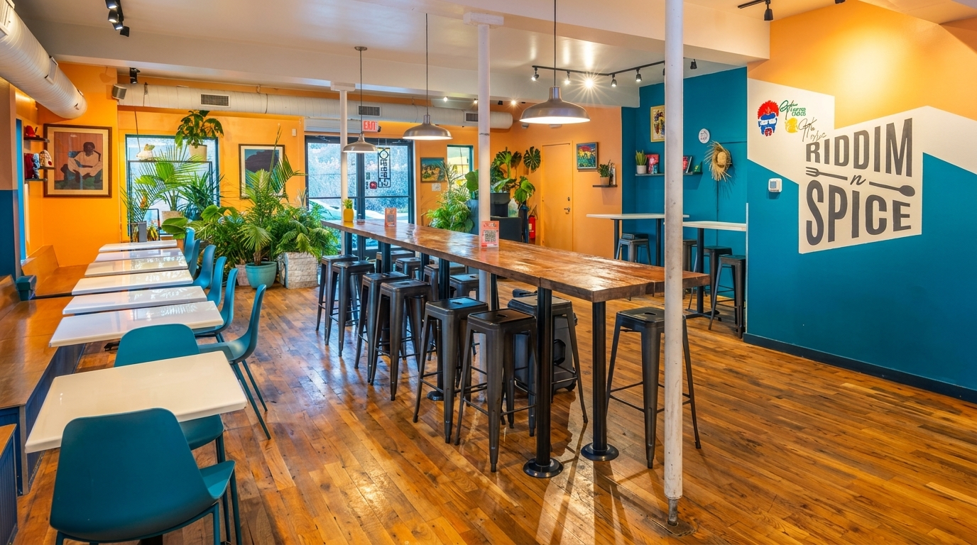 Vibrant Riddim N Spice restaurant interior with long communal tables, teal chairs, and orange and blue walls.