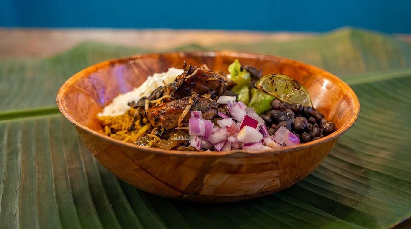 A wooden bowl filled with rice, jerk chicken, black beans, red onions, and a lime wedge.