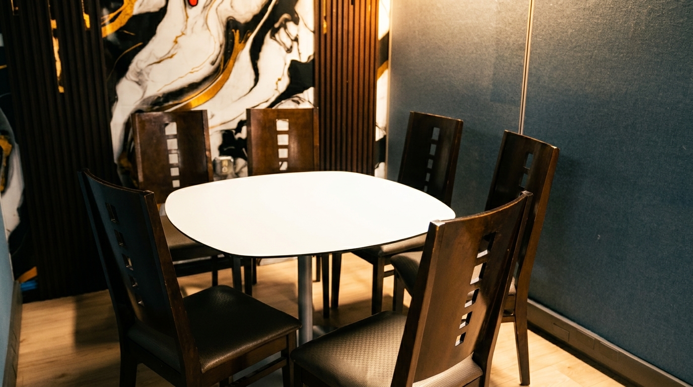 A private dining nook with a white table surrounded by six dark wooden chairs, against a patterned wall.