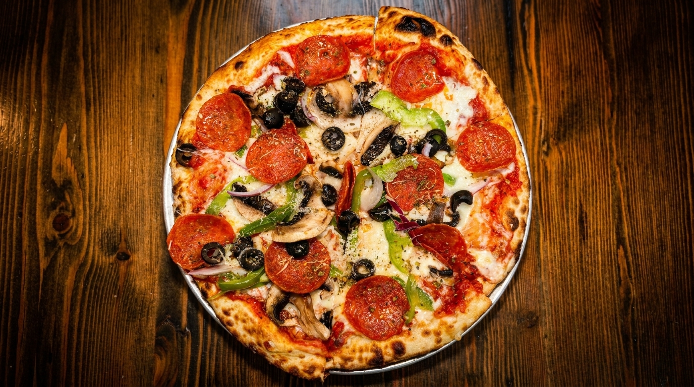 Whole pepperoni pizza with green peppers, black olives, mushrooms, and red onions on a wooden table.