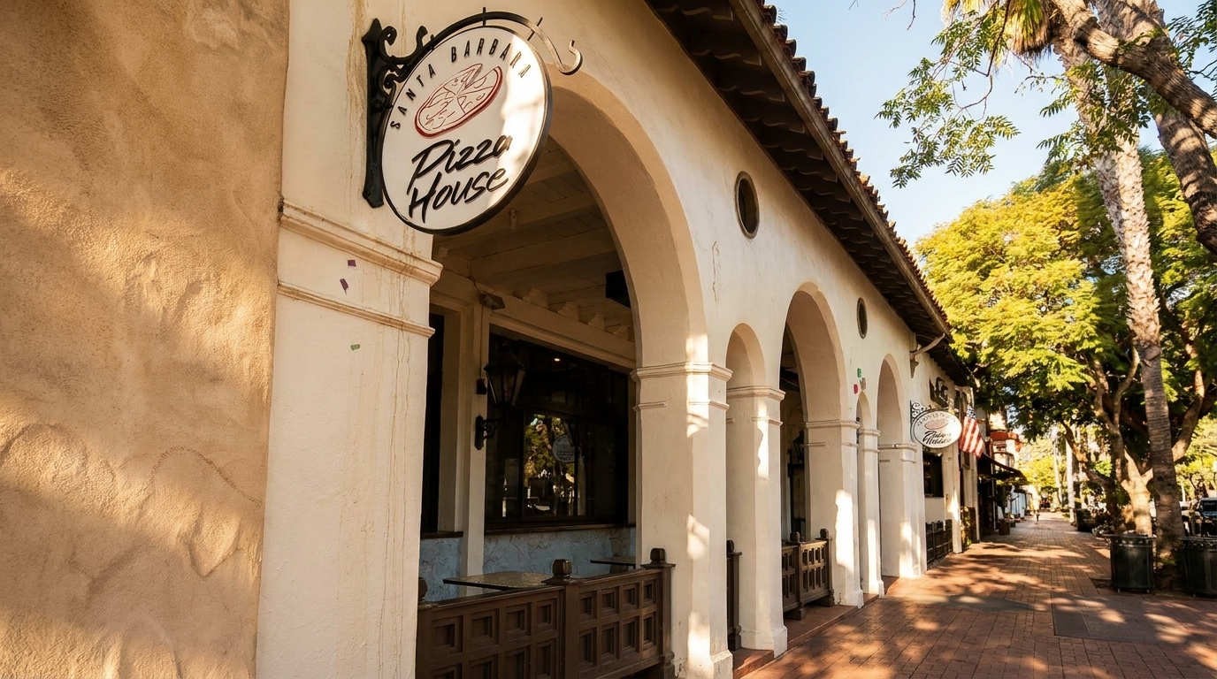 Santa Barbara Pizza House sign on a building with arches and a tree-lined sidewalk.