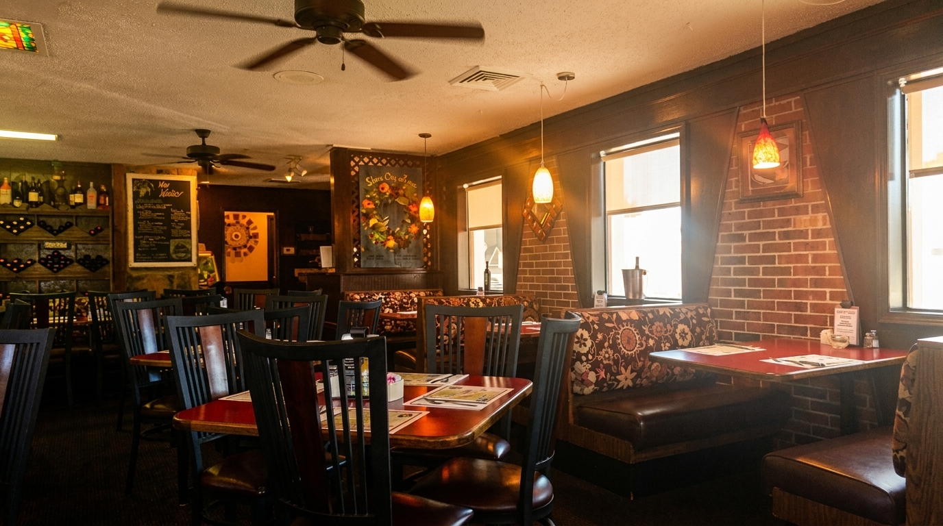 Cozy restaurant interior with dark wood tables, booth seating, brick accents, and warm lighting.