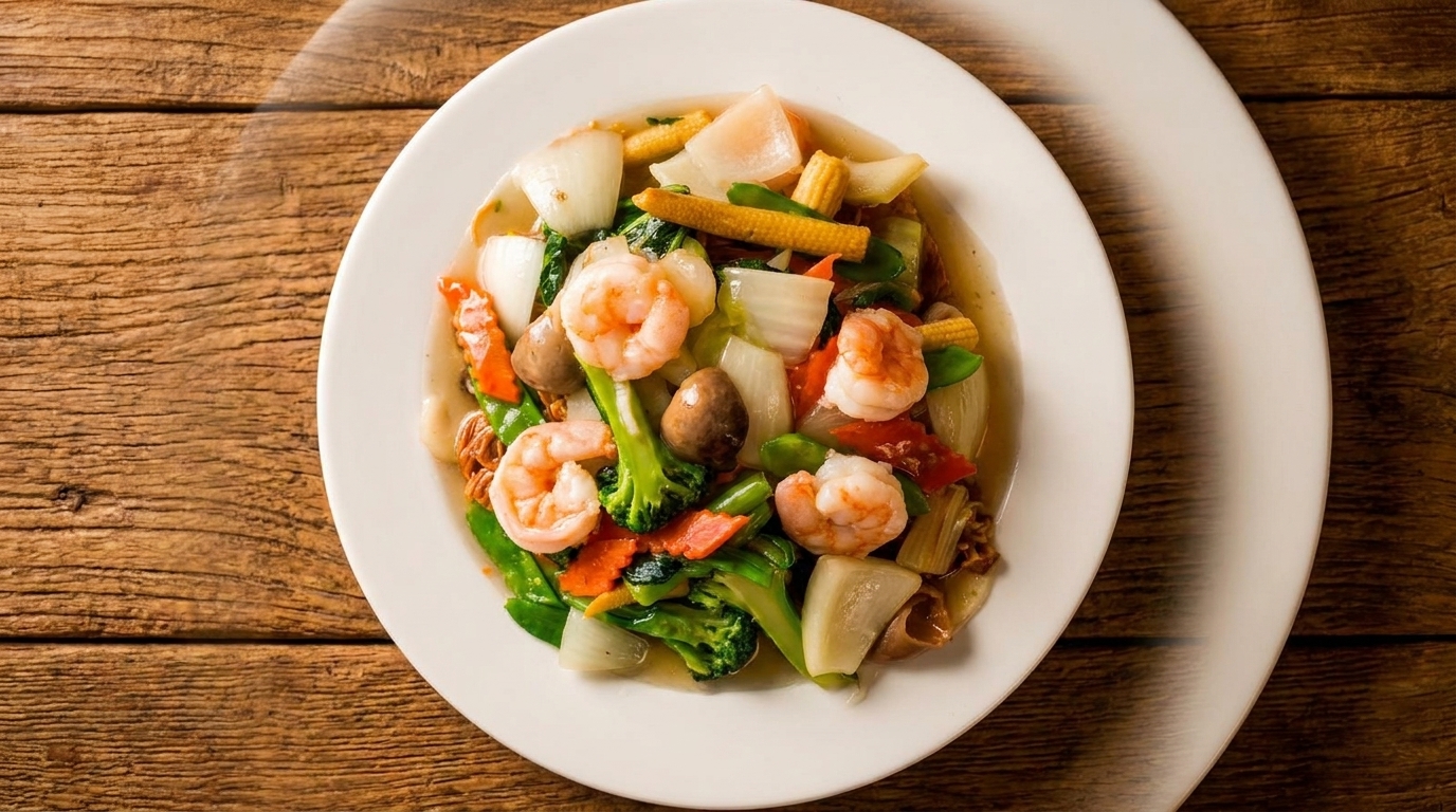 Stir-fried shrimp and mixed vegetables, including broccoli, carrots, and baby corn, on a white plate.
