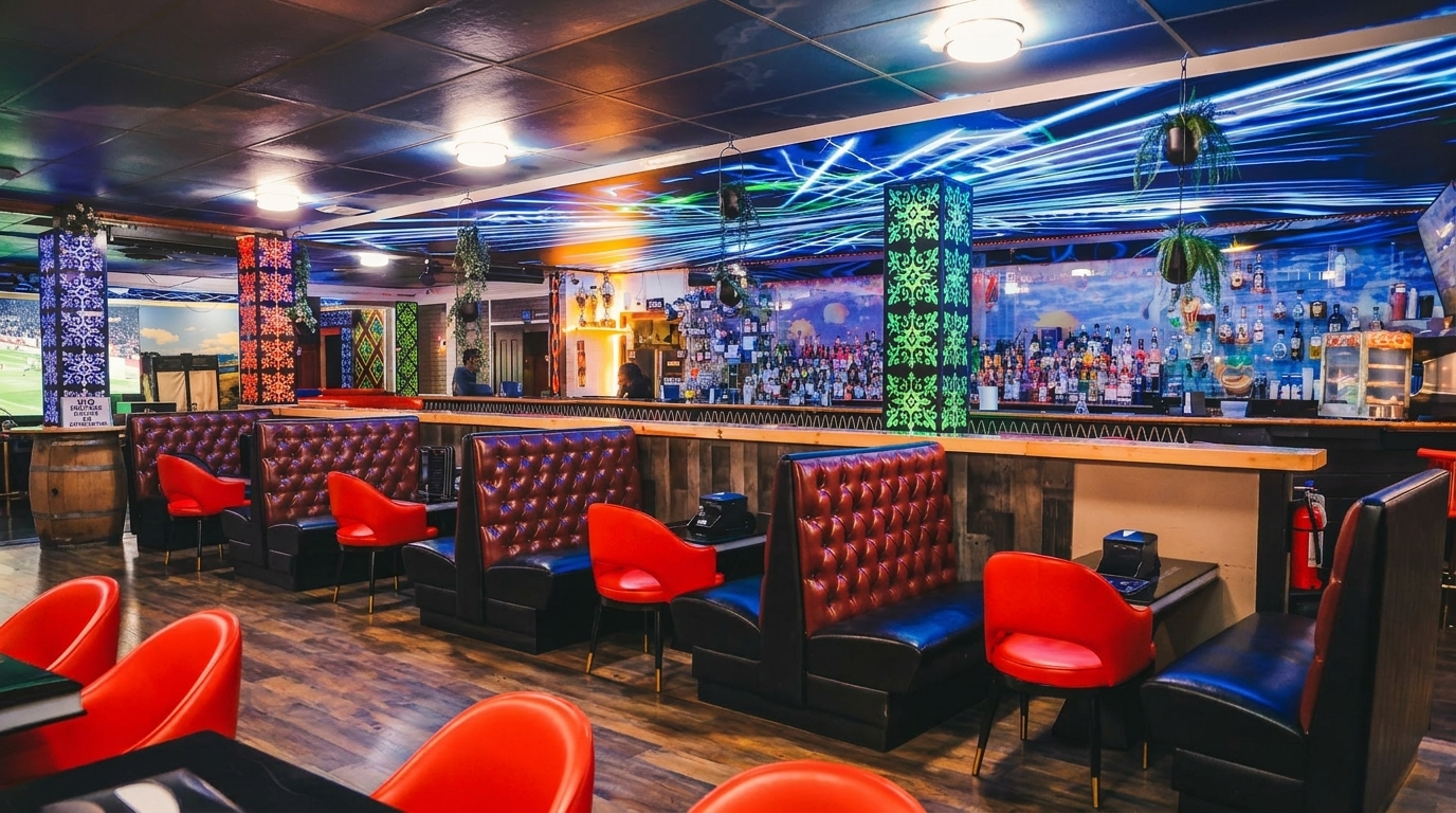 Interior of a vibrant bar with red booths, red chairs, and a long bar stocked with bottles.