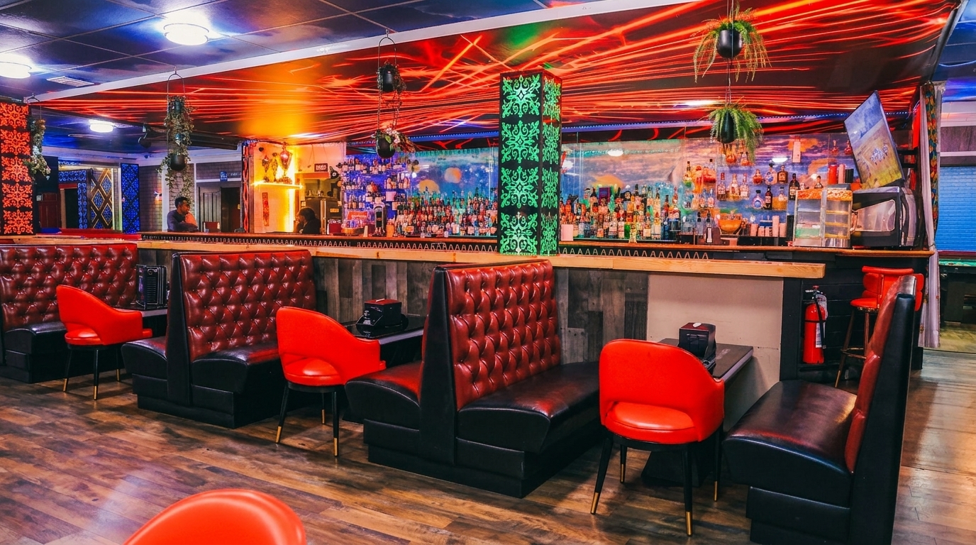 A vibrant bar interior with red tufted booths, red chairs, and a long bar with many bottles.