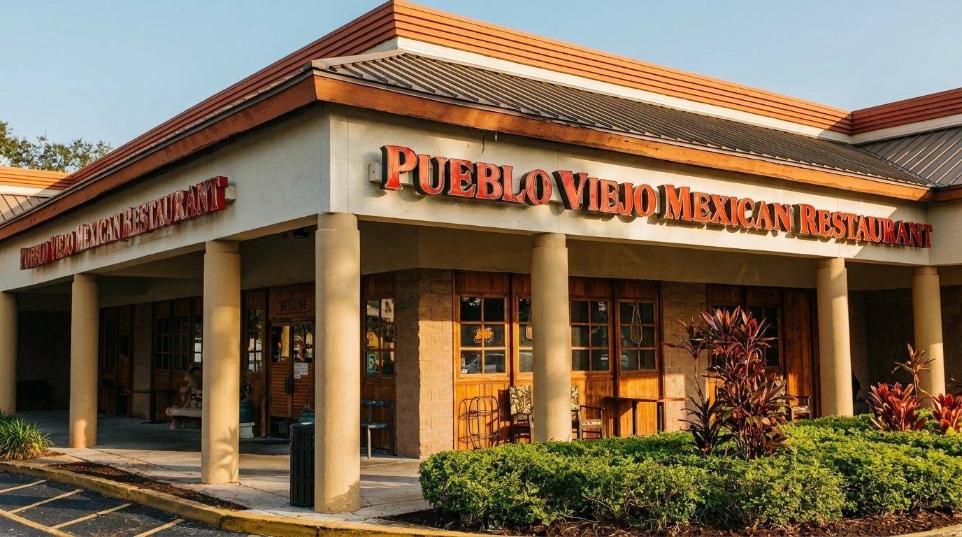 Exterior of Pueblo Viejo Mexican Restaurant with red signage, columns, and green landscaping.