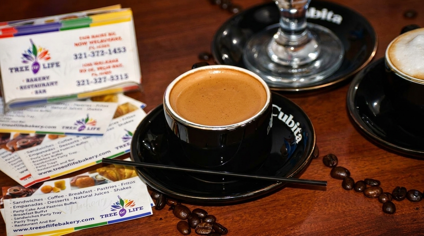 Two cups of coffee, one espresso and one latte, on a wooden table with coffee beans and business cards.