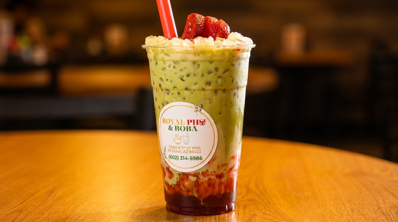 Royal Pho & Boba's matcha boba tea with strawberries and a red straw on a wooden table.