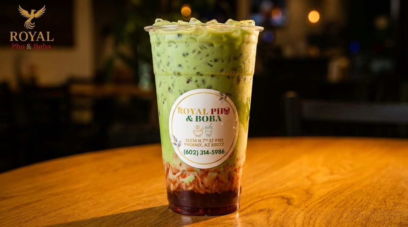 Royal Pho & Boba's green boba drink with dark brown syrup on a wooden table.