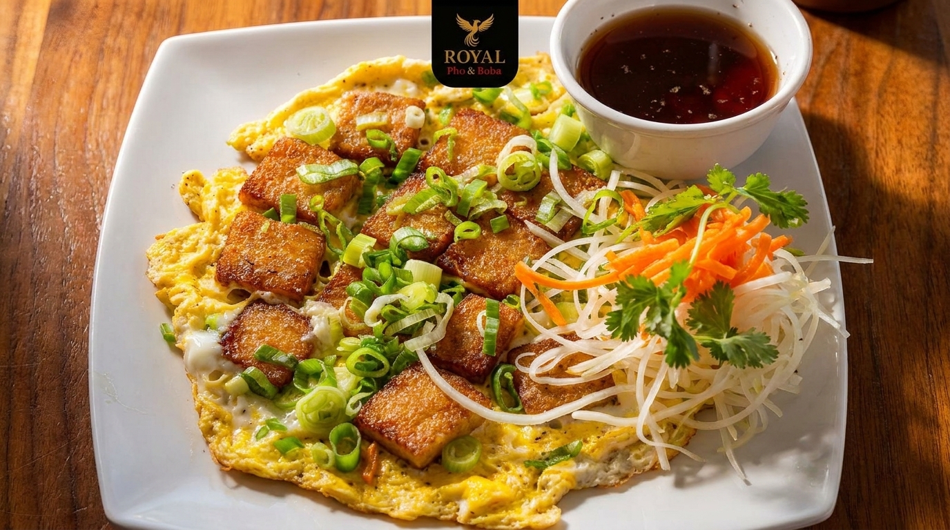 A plate of Vietnamese fried rice flour cake with egg, green onions, and shredded vegetables.