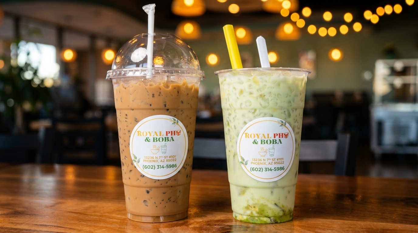 Two Royal Pho & Boba drinks, one coffee and one green, on a wooden table.