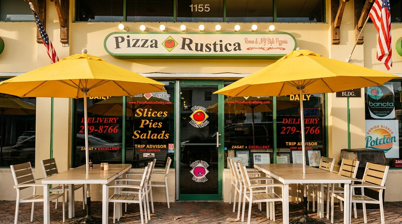 The exterior of Pizza Rustica, a Roman & NY Style Pizzeria, with outdoor seating under yellow umbrellas.