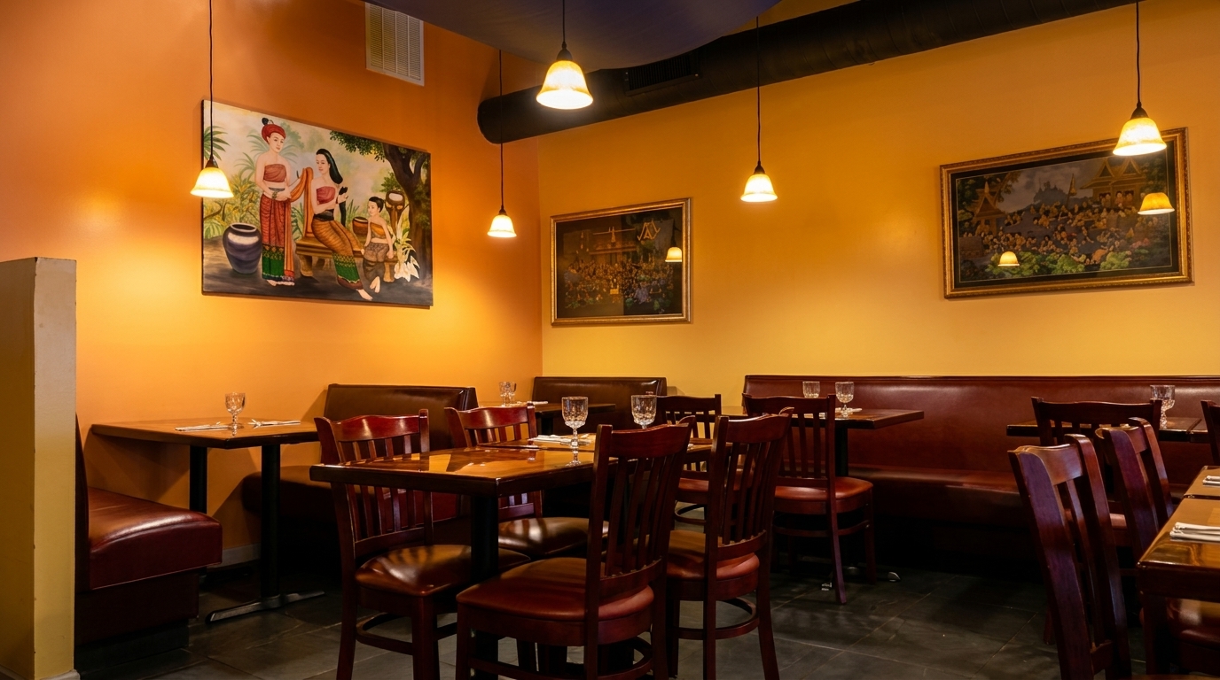 Cozy restaurant interior with orange walls, framed artwork, dark wood tables, and brown leather booths.