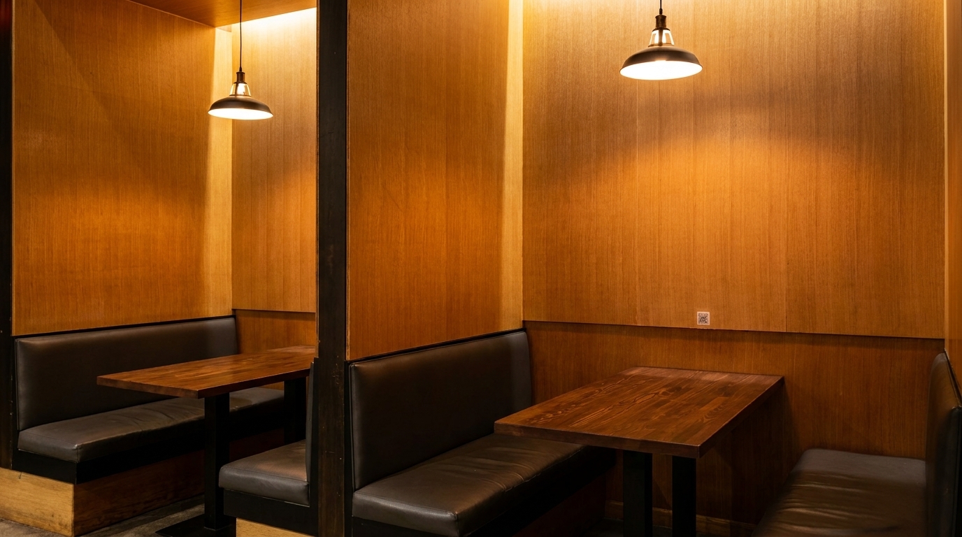 Cozy restaurant booths with dark leather seating, wooden tables, and warm pendant lighting.