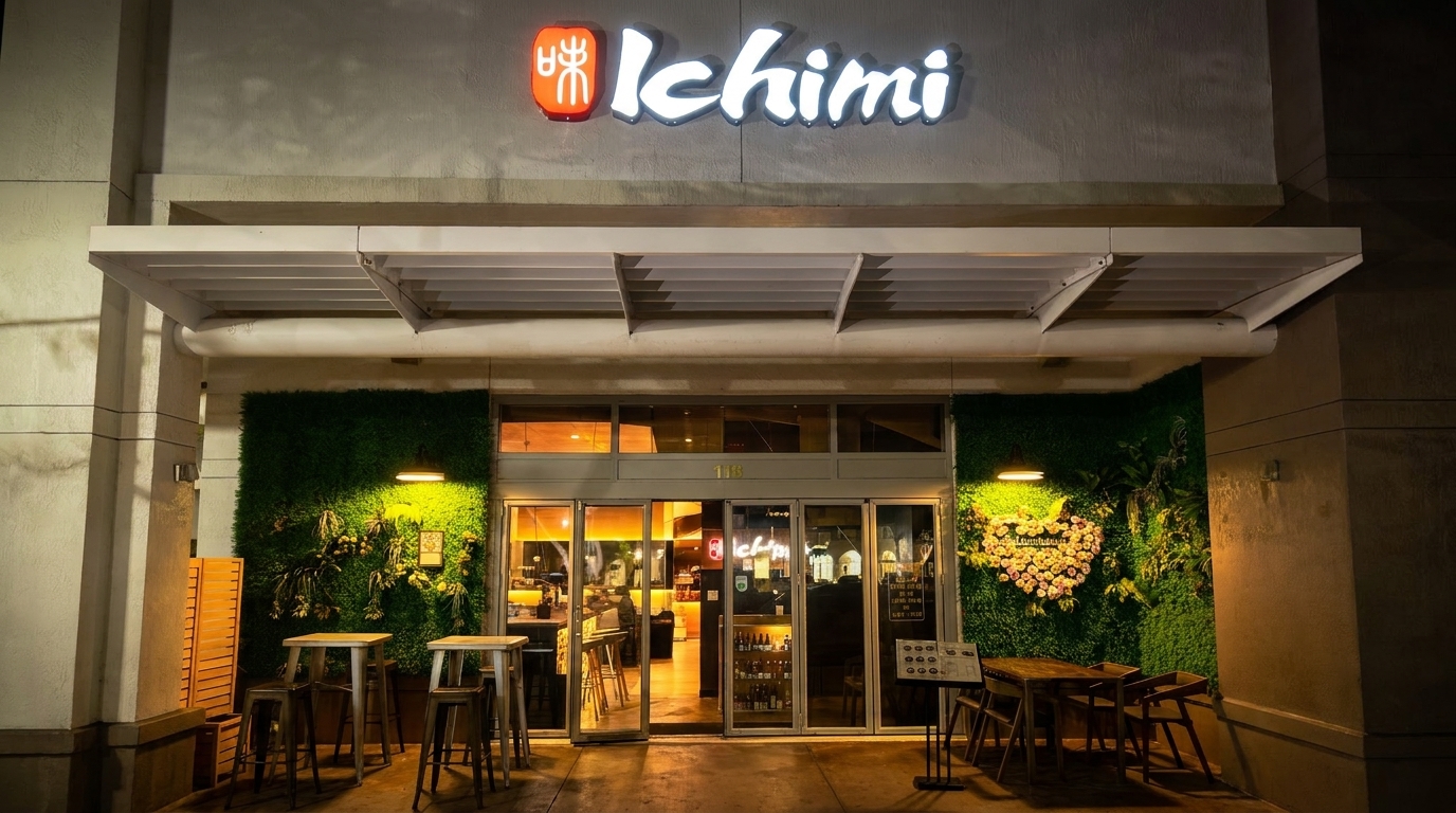 The Ichimi restaurant exterior at night, with a glowing sign, green wall, and outdoor seating.