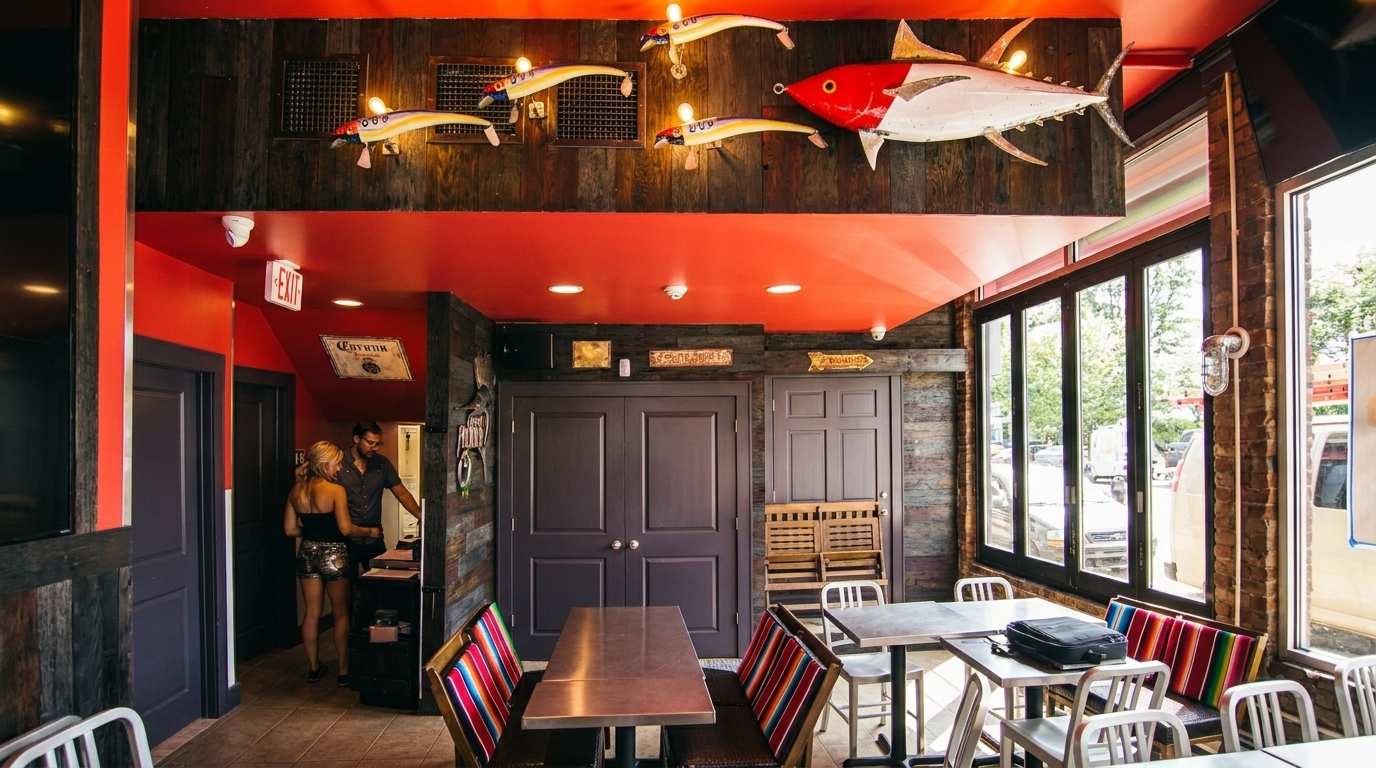 Restaurant interior with red ceiling, wooden walls, fish decor, and colorful striped bench seating.