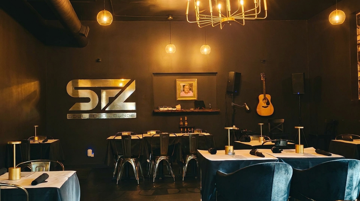 Dark dining room with gold accents, set tables, a guitar on the wall, and a "STZ Soul Food Lounge" sign.