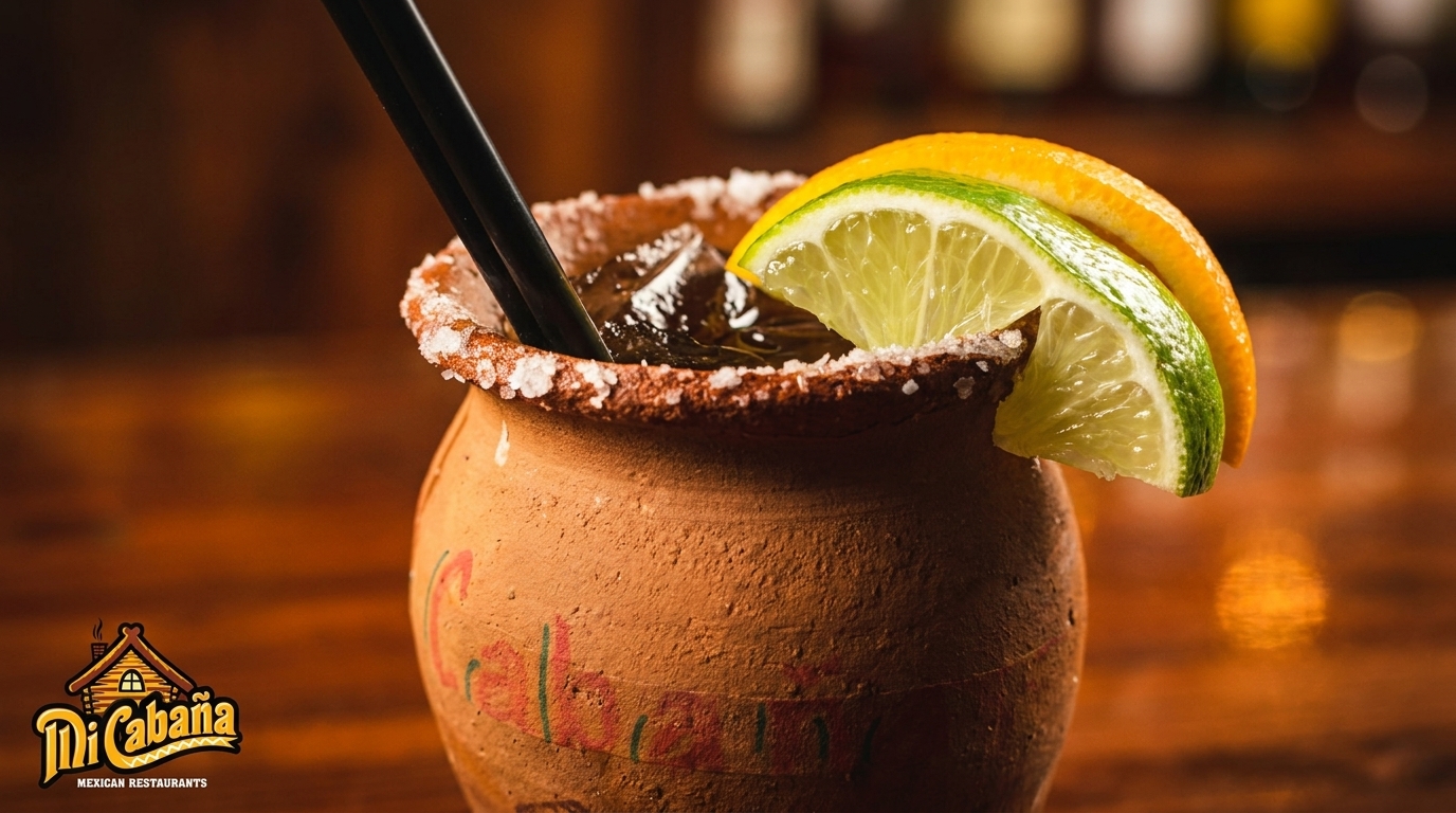 A traditional Mexican cantarito cocktail in a clay mug, garnished with lime and orange slices.
