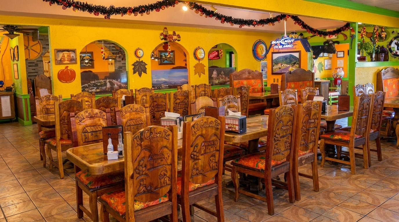 A vibrant Mexican restaurant interior with yellow walls, colorful decor, and many carved wooden tables and chairs.